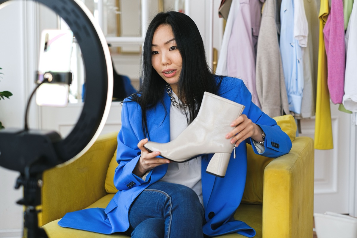 Seller live-streaming a product review on a smartphone with a ring light.